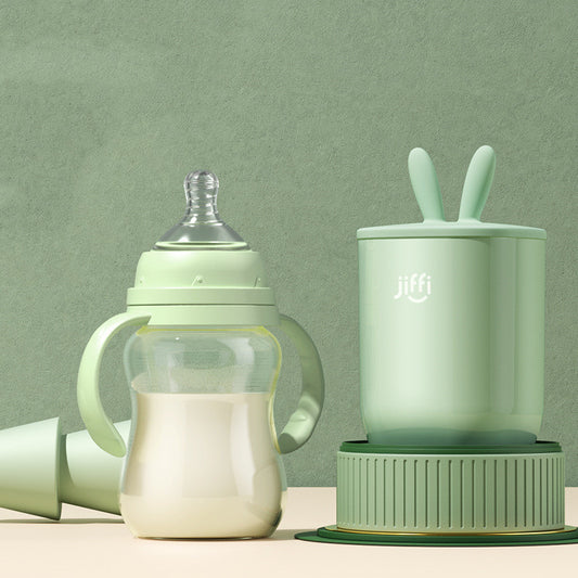 "Green baby bottle and matching training cup set placed on a light green background, designed for infant feeding and transition."