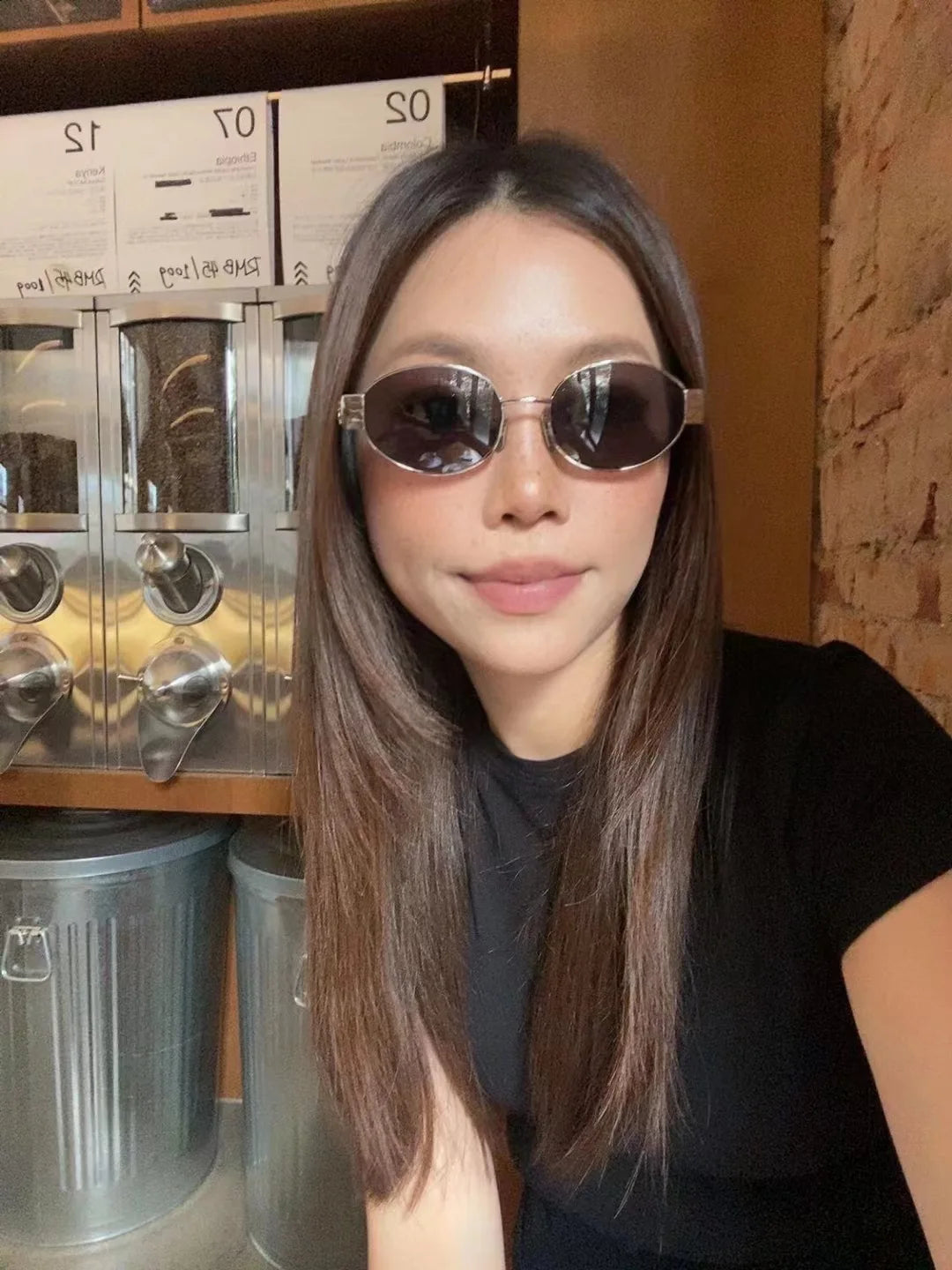 Trendy woman wearing retro oval sunglasses – lifestyle shot with coffee machine background