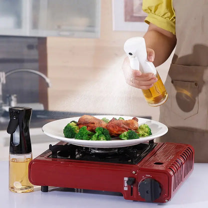 
"Person using a spray bottle to apply oil or seasoning over a plate of food on a portable stove in a modern kitchen setting."